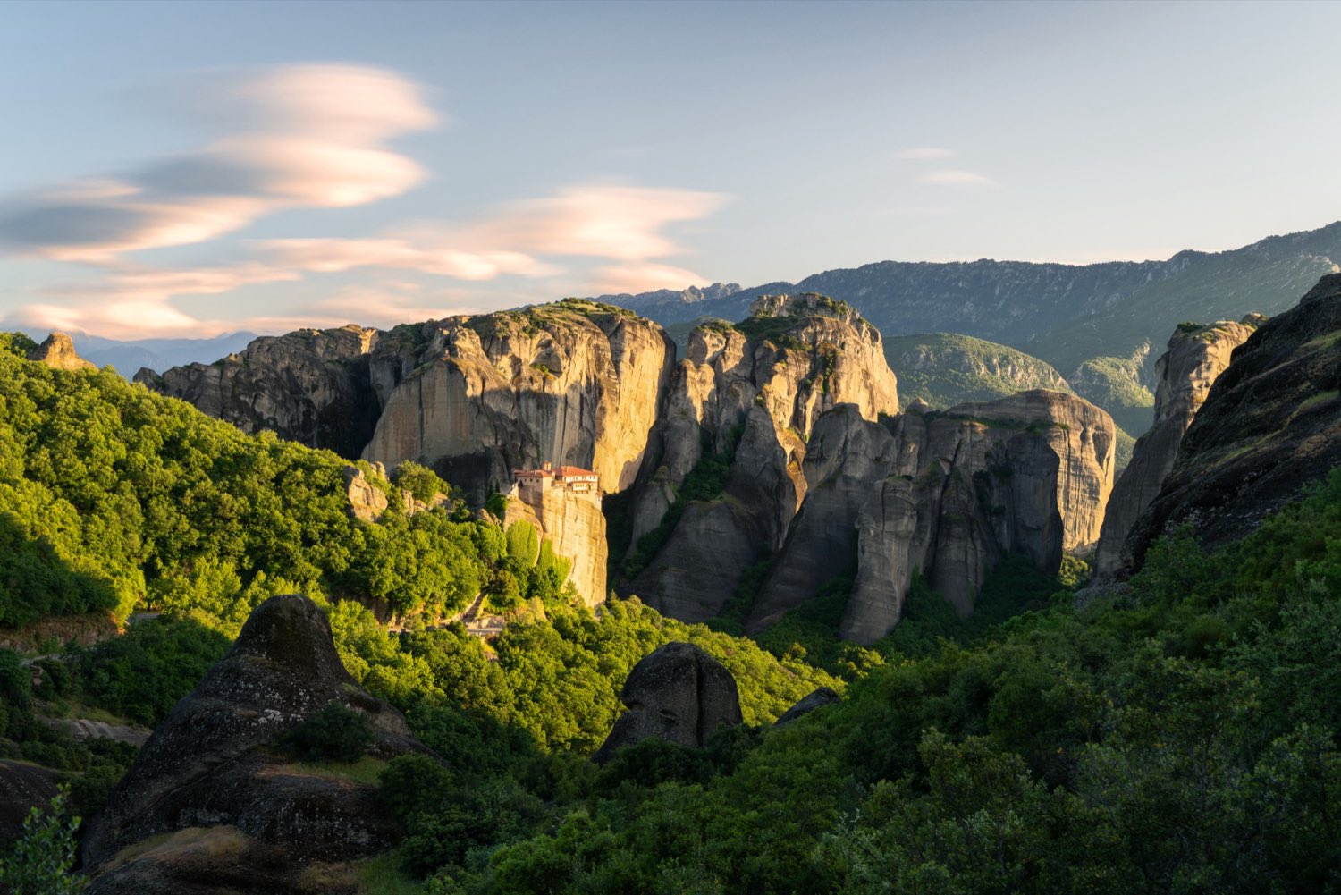Golden light raking across sandstone cliffs under lenticular clouds