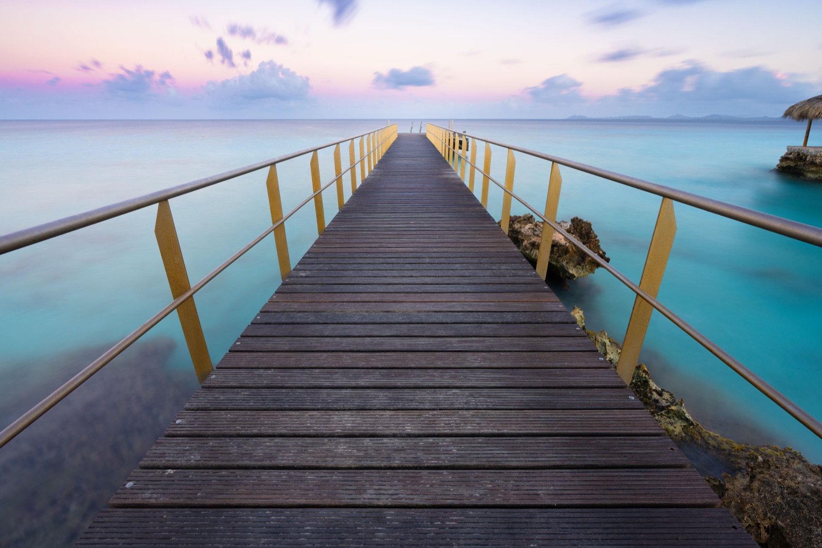 A wooden jetty leading the eye to a windmill at dawn