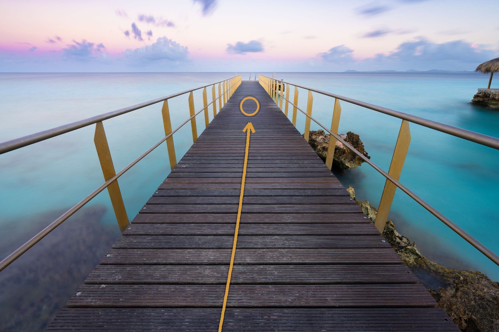 A wooden pier receding to a vanishing point on the horizon at dusk, its converging lines traced in amber leading the eye into the frame