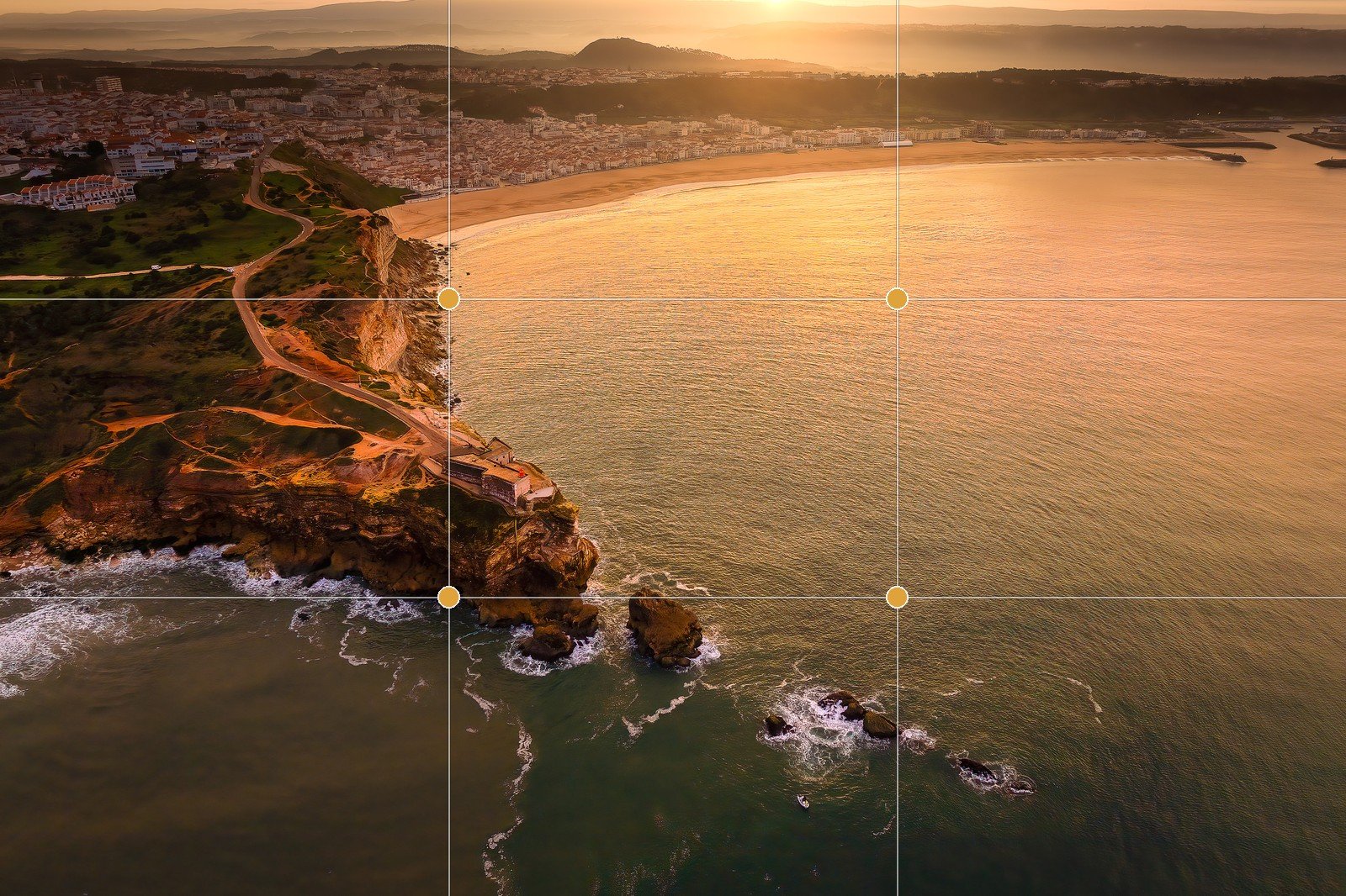 The rule-of-thirds grid overlaid on an aerial coastal landscape at sunset — the horizon on the upper third, the sunlit headland on the left-hand power points