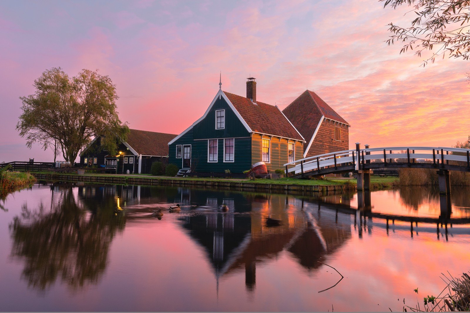 A Dutch farmhouse mirrored in still water at sunset, a symmetrical reflection